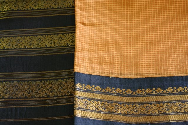 A burnt orange cotton gadwal with a black and gold border and self checks