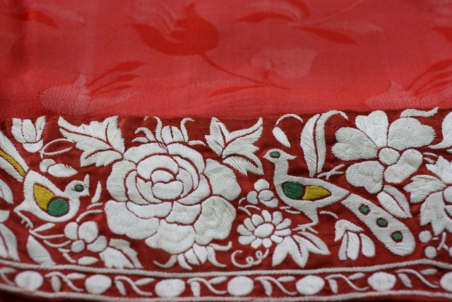 An antique kor ni saree or border saree showing peonies and peacock on red crepe silk with self-weave.